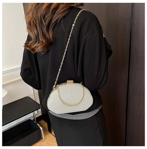 Detail of silver glitter clutch bag with gold chain strap shown on model shoulder