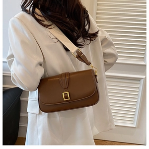 Brown leather crossbody bag with wide canvas strap shown on a model in white blazer