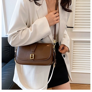 Detail of vintage brown leather bag featuring a gold buckle and white woven strap