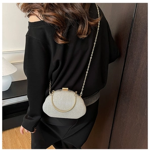 Detail of silver sequin evening bag featuring a gold chain and circular metal handle