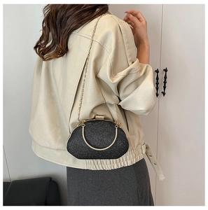 Detail of glitter evening box bag with gold metal handle and chain strap on model