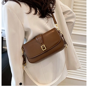 Detail of vintage dark brown leather crossbody bag with a polished gold square buckle