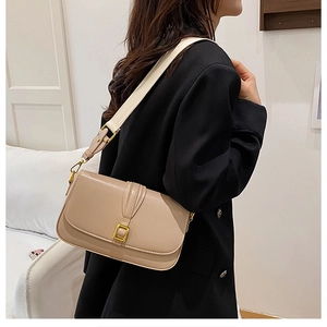 Detailed side view of khaki leather shoulder bag with gold buckle and wide strap