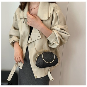 Chic black glitter cloud evening bag with gold chain and handle on a leather jacket