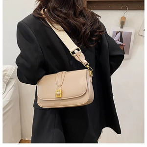 Detail of beige leather crossbody bag with gold buckle and wide fabric shoulder strap