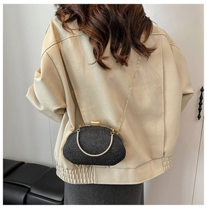 Elegant black sequin evening bag with gold chain strap shown on model shoulder
