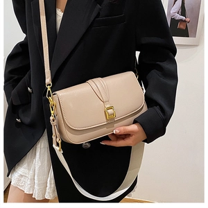 Detail of a beige leather flap crossbody bag with a gold buckle and stylish wide strap