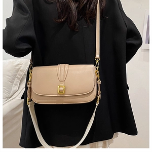 Detail of beige flap square bag with gold hardware and dual interchangeable shoulder straps