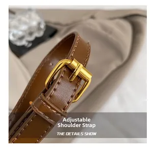 Close-up of adjustable brown leather shoulder strap with gold buckle and stitching