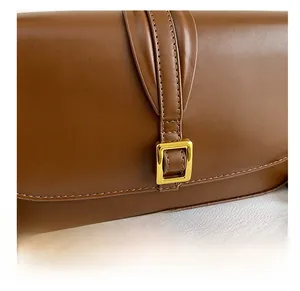 Detail of brown leather bag showing fine stitching and gold square metal buckle