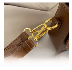 Detail of the high-quality gold metal hook and leather strap on a brown crossbody bag