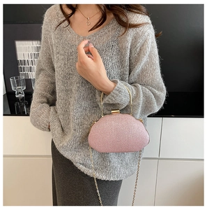 Detail of pink glitter evening clutch bag with gold handle and chain on model