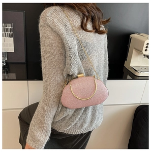 Detailed view of pink glitter evening bag with gold ring handle and metal chain strap