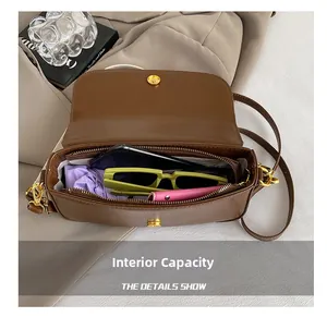 Internal capacity of brown leather bag showing phone, sunglasses, and wallet detail