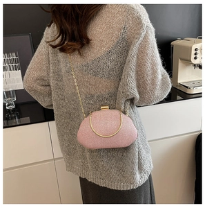 Pink metallic woven clutch bag with gold handle and chain shown on model in modern setting
