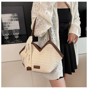Detail of hand-woven beige tote bag with dark brown leather handles and decorative ribbon