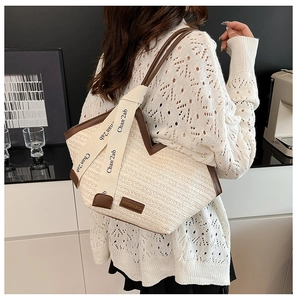 Detail of contrast stitch woven tote bag with dual straps and leather fashion label