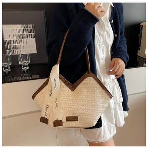Detail of woven tote bag featuring brown leather trim and decorative ribbon with text