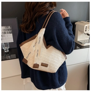 Close-up of the straw woven tote bag featuring brown leather trim and decorative ribbons