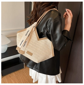 Detail of beige straw tote bag featuring brown PU leather trim and branded webbing handles