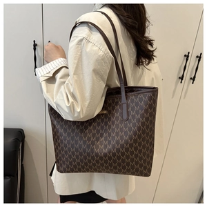 Détail du sac cabas marron foncé avec motif de lettres M et plaque logo en métal