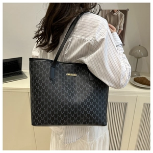 Détail du grand sac cabas avec imprimés de lettres M et plaque en métal doré