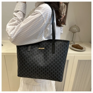 Détail d'un grand sac cabas noir avec imprimé lettres M et logo en métal doré
