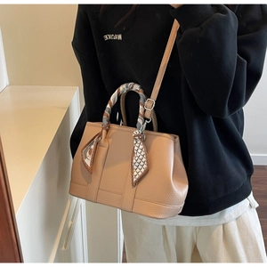 Detail of beige bucket bag with litchi grain leather and silk scarf handle accent
