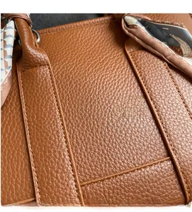 Close-up of brown litchi grain leather texture and fine stitching with decorative silk scarf