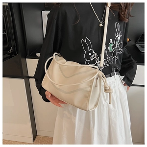Detail view of cream pleated cloud bag featuring delicate side knot and V-shaped stitching