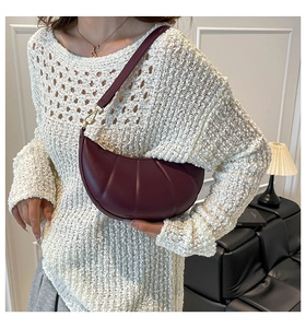 Close-up of burgundy crescent dumpling bag with pleated faux leather and gold hardware