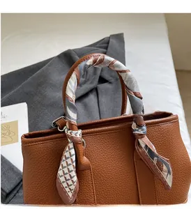 Detail of brown litchi pattern leather handbag with elegant printed silk scarf handle