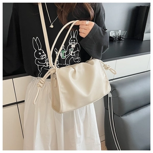 Détail d'un sac à bandoulière plissé crème avec bandoulière nouée et design nuage