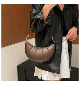 Detail of a dark brown pleated hobo bag with gold zipper and adjustable strap