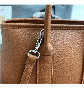Detail of brown litchi leather bag with silver metal swivel hook and floral silk scarf handle