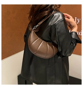 Detail of dark brown pleated crescent bag with leather strap and silver metal buckle