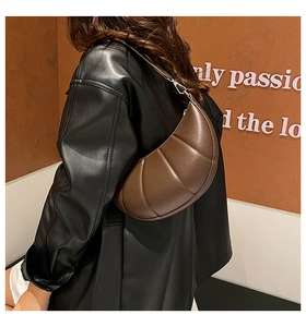 Detail view of a quilted dark brown crescent shoulder bag worn by a model in soft lighting