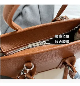 Detail of silver zipper closure and silk scarf on brown textured leather bucket bag