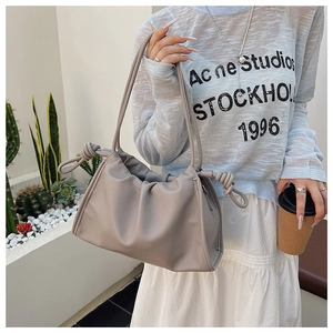 Détail du sac nuage en cuir froncé avec nœuds décoratifs porté dans un café urbain