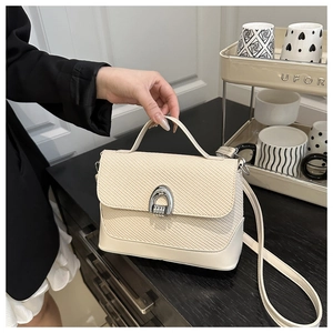 Détail du sac à main tissé blanc cassé avec une boucle en métal argenté en fer à cheval