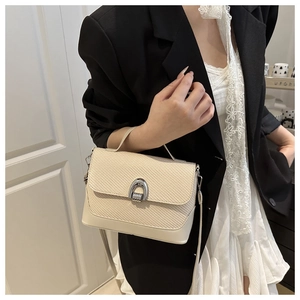 Detail of off-white woven bag with a silver horseshoe buckle on a stylish model