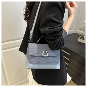 Detail of light blue crossbody bag with diagonal woven texture and silver horseshoe lock
