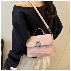 Detail of pink woven leather crossbody bag worn by model with silver horseshoe clasp