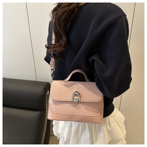 Detail of pink crossbody bag with woven texture, smooth leather and silver horseshoe buckle