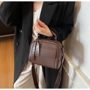 Close-up of brown litchi pattern leather handbag with adjustable wide strap and rivet details