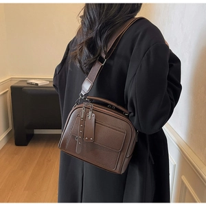 Detail of dark brown lychee leather crossbody bag with wide strap on shoulder