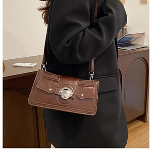 Détail d'un sac à bandoulière marron avec boucle ronde argentée et rivets métalliques chic