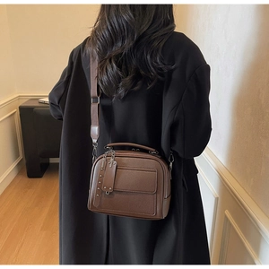 Detail of vintage brown litchi pattern leather handbag with metal stud tag and wide strap