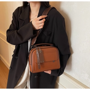 Detailed shot of brown litchi pattern leather crossbody bag with wide fabric strap