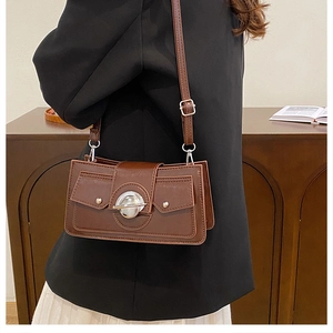 Détail du sac bandoulière marron vintage avec fermoir rotatif argenté et texture cuir PU fin